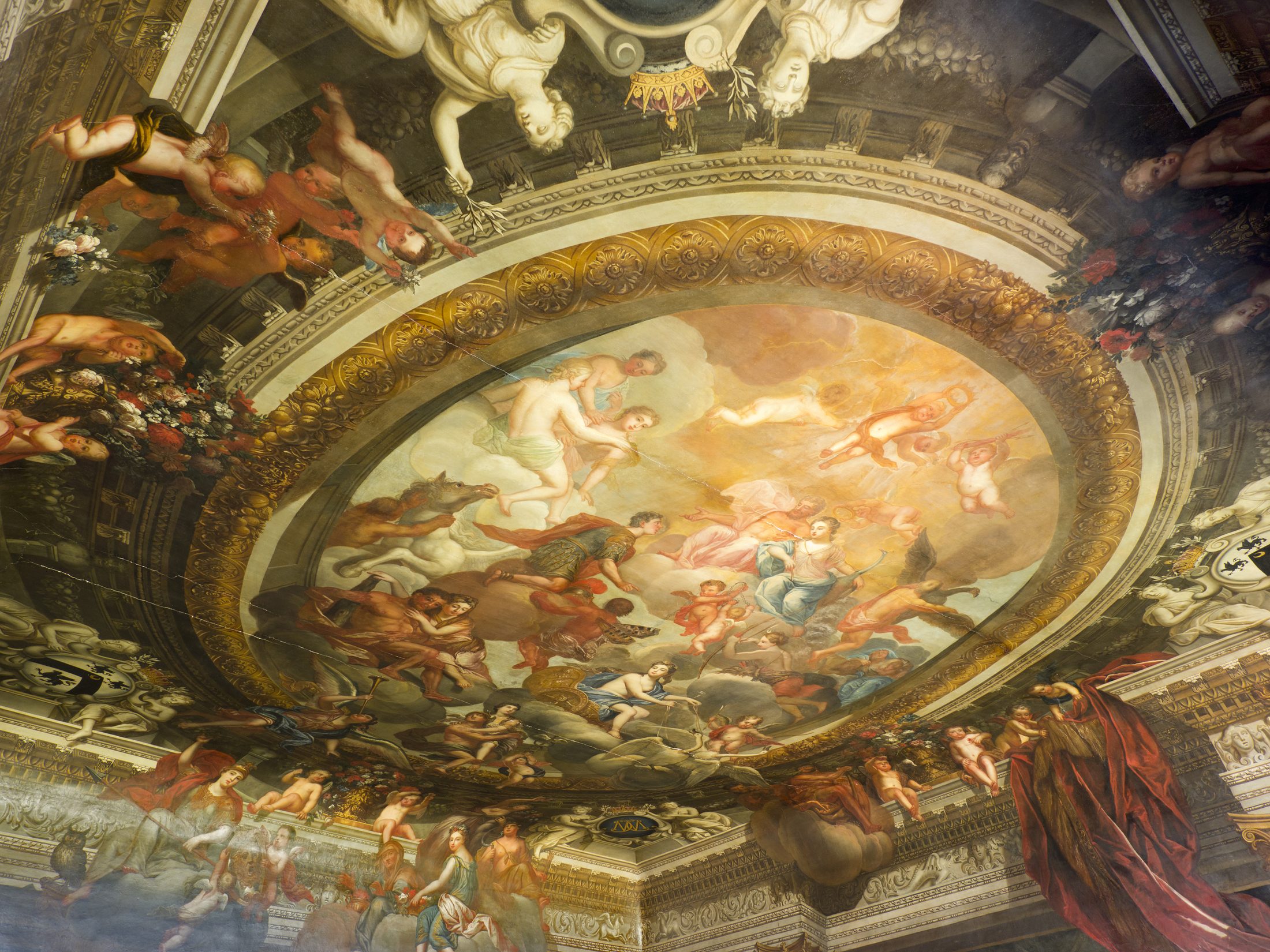 A wide, angled view of the Great Stair's painted ceiling, with cherubs and floral swags around the central oval
